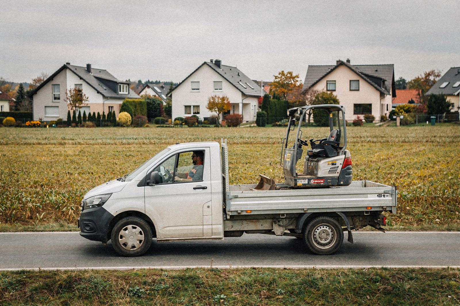 Transporter mit Kipphänger und Minibagger auf einer Landstraße in Anhalt