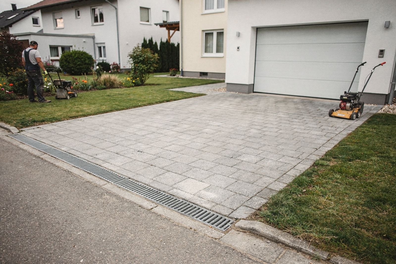 Hofeinfahrt aus grauem Betonpflaster mit Randeinfassung vor einem Einfamilienhaus